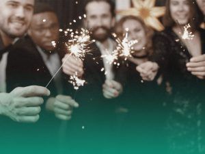 Estudantes comemorando a formatura em trajes de gala na cor preta e segurando velas estrelinha.