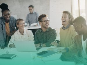 Grupo de estudantes rindo e se divertindo na sala de aula enquanto usam um laptop para criarem seus sites de formatura.